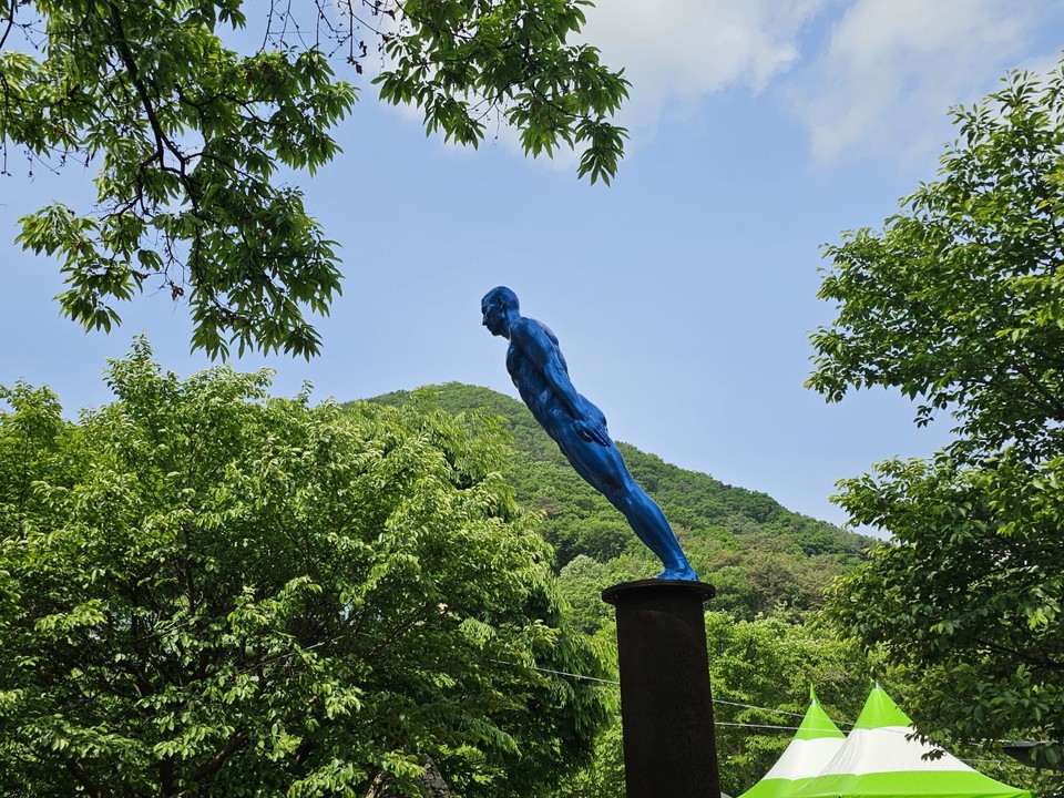 20일 오전 11시께 양주 장흥면 장흥조각공원에 있는 김지현 작가의 ‘36.5도 인간 - Blue’ 작품이 구름 조금 낀 하늘과 푸른 나뭇잎을 배경으로 더욱 돋보이고 있다. (사진=강상준 기자)