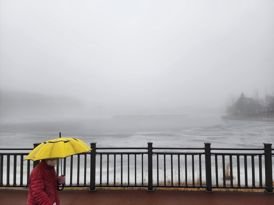 겨울비가 내리는 13일 오후 4시10분께 안개 낀 이천 설봉호수를 노란우산을 쓴 한 시민이 걷고 있다. (사진=송석원 기자)